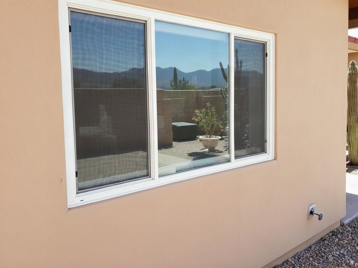 Illustrative example: the same wall with a new white vinyl double-pane window, clear glass, fresh caulk and clean stucco after window replacement